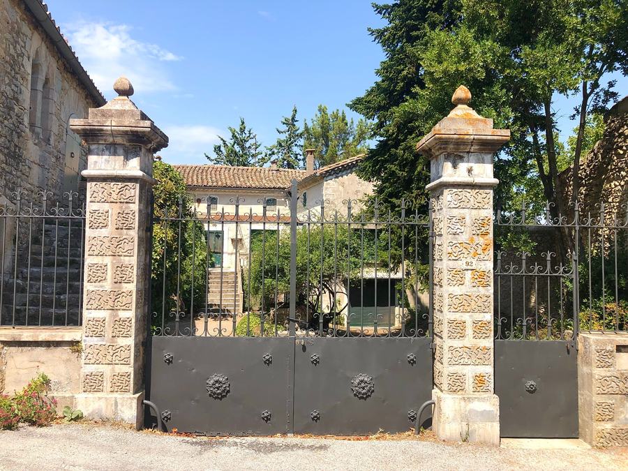 Deux piliers en pierre d'un portail en fer forgé devant une maison