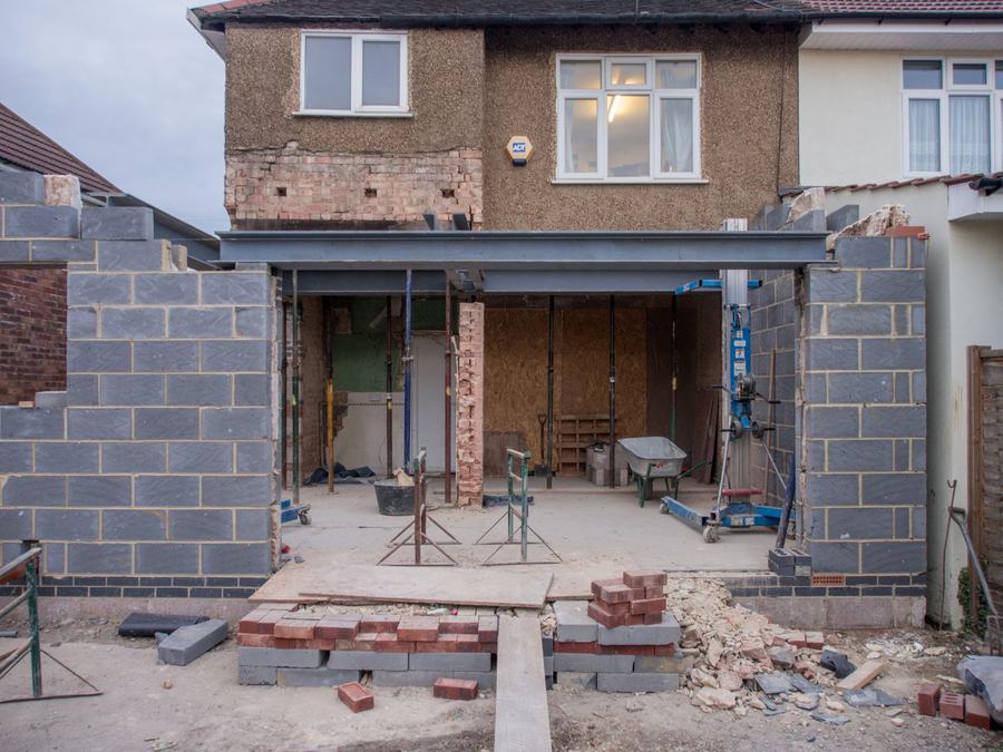 Maison en brique dont l'arrière est ouvert pour une extension montée en parpaings